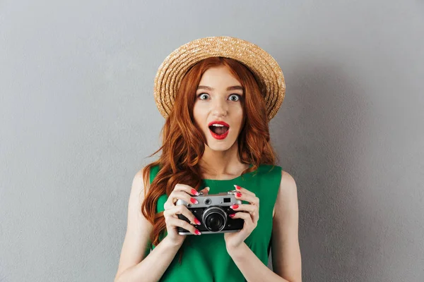 Rödhårig ung chockad dam fotograf håller kameran. — Stockfoto