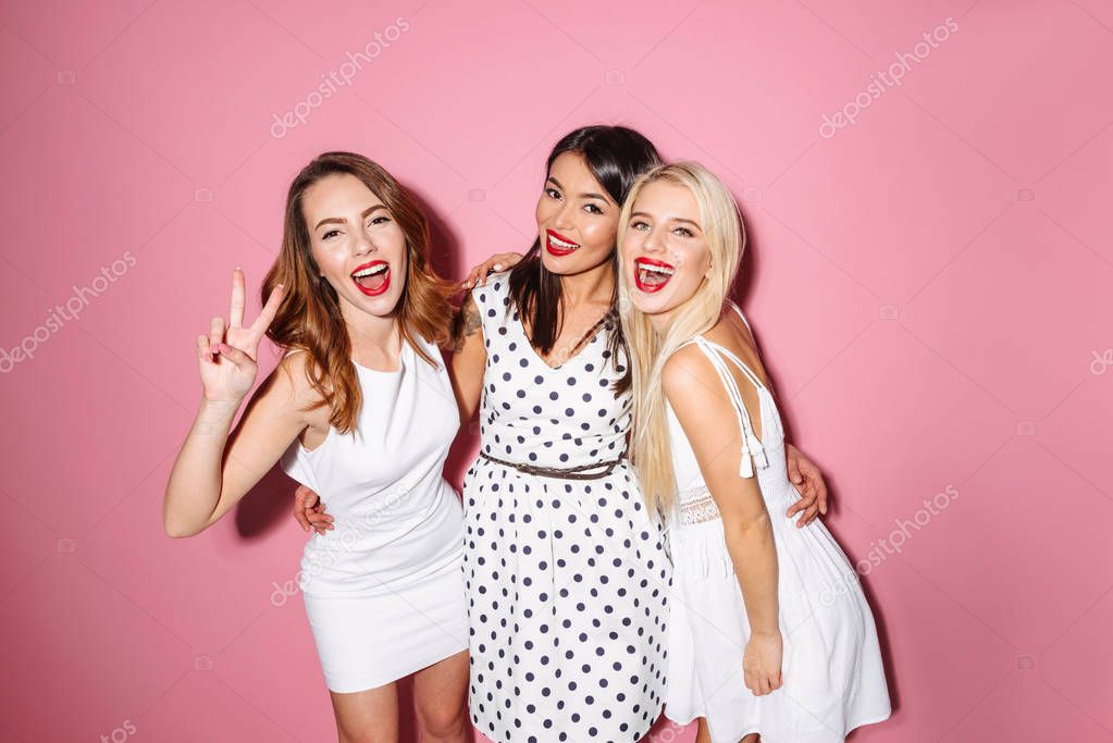 Three happy young ladies showing peace gesture