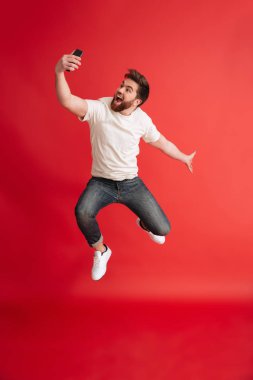 Cep telefonu yapmak selfie kullanarak atlama sakallı adam izole.