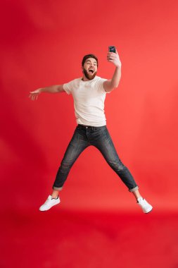 Cep telefonu yapmak selfie kullanarak atlama sakallı adam izole.