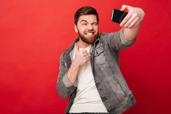 Homem engraçado fazendo selfie no smartphone e mostrando o polegar para cima — Fotografia de Stock