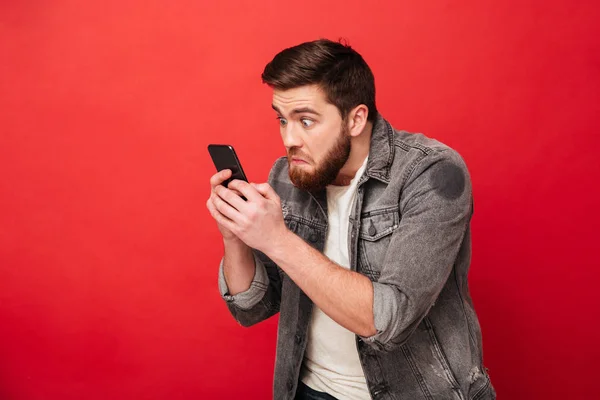 Imagen del hombre barbudo sorprendido escribiendo mensaje en el teléfono inteligente — Foto de Stock