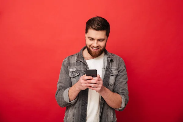 Foto de Smiling barbudo hombre escribiendo mensaje en el teléfono inteligente — Foto de Stock