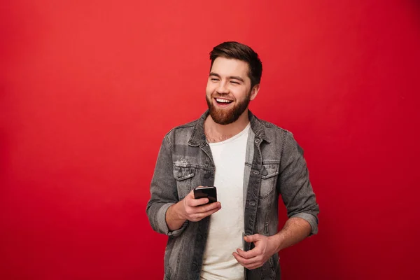 Gülme görüntüsünü smartphone tutarak ve uzağa bakarak adam sakallı — Stok fotoğraf