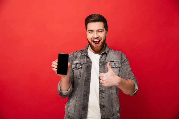 Imagen del hombre feliz sin afeitar mostrando el teléfono celular en la cámara y ges — Foto de Stock