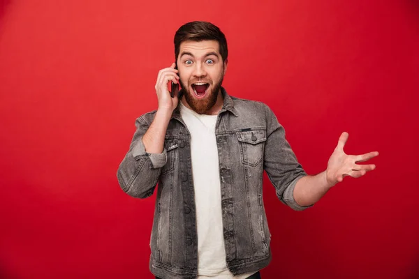 Foto de homem bonito animado expressando surpresa no rosto enquanto — Fotografia de Stock