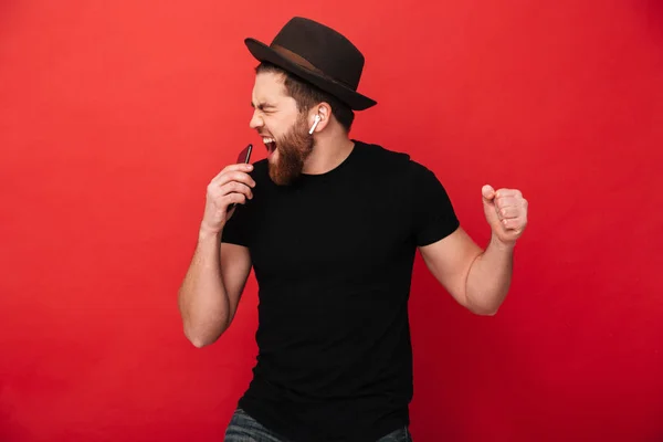 Bild av glada kille klädd i svart t-shirt och mössa sång och li — Stockfoto