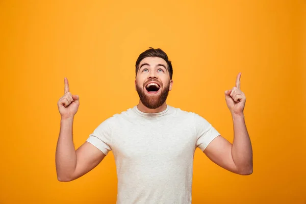 Retrato de un hombre barbudo feliz apuntando con los dedos hacia arriba — Foto de Stock