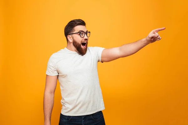 Retrato de un hombre barbudo excitado con gafas apuntando — Foto de Stock