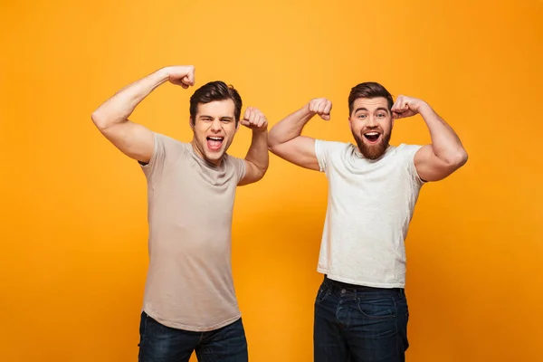 Porträtt av en två glada unga män visar biceps — Stockfoto