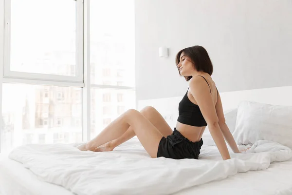Ritratto di una giovane donna seduta sul letto — Foto Stock