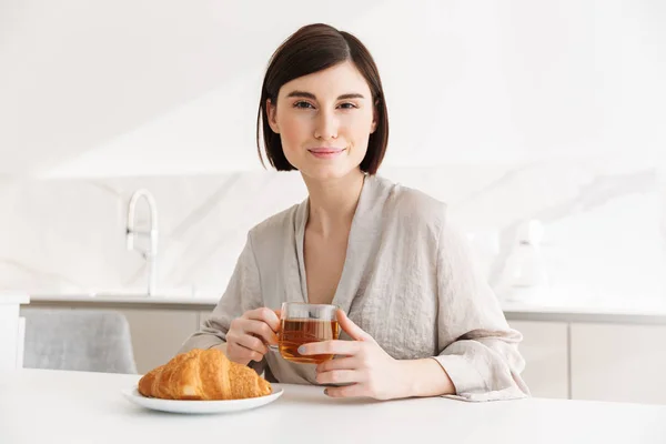 Imagen de la atractiva mujer de la mañana en bata desayunando en ho — Foto de Stock