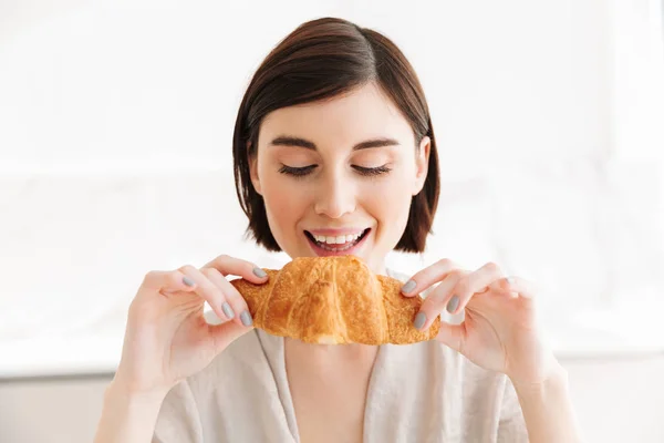 Mulher encantadora e com fome 20s em roupão tomando café da manhã em apartmen — Fotografia de Stock