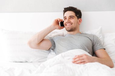 Esmer çekici adam rahat t-shirt gülümseyen görüntüsünü süre