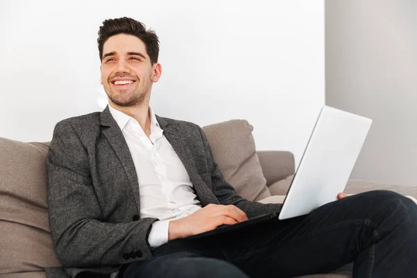 Χαμογελαστός άνθρωπος των επιχειρήσεων κάθεται στον καναπέ στο σπίτι — Φωτογραφία Αρχείου