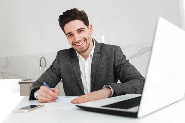 Счастливый бизнесмен сидит за столом с ноутбуком — стоковое фото