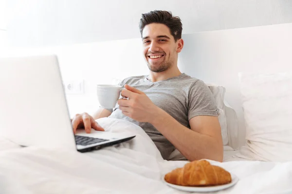 Foto av lycklig man i casual kläder att ha frukost, medan ligg — Stockfoto