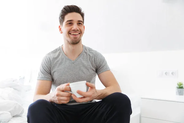 Фото щасливого ранкового чоловіка в футболці посміхається, сидячи в — стокове фото