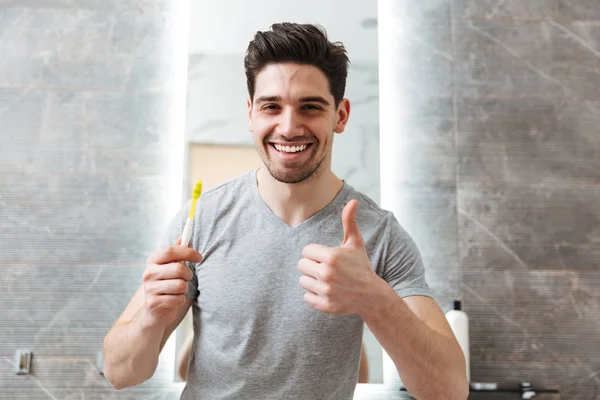 Lycklig brunett man borsta hans tänder i badrum — Stockfoto