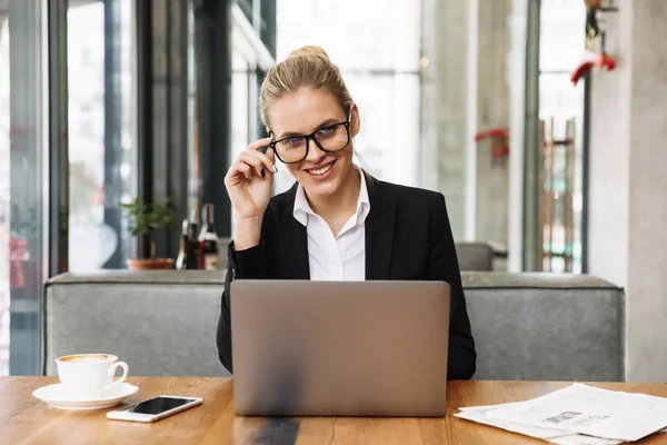 Mujer de negocios rubia feliz sentado junto a la mesa en la cafetería — Foto de Stock