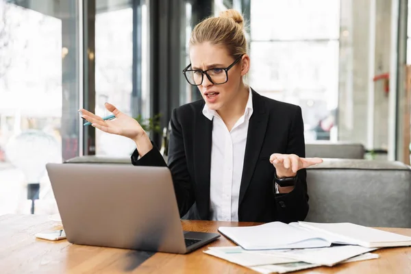 Mujer de negocios rubia confusa sentada junto a la mesa en la cafetería — Foto de Stock