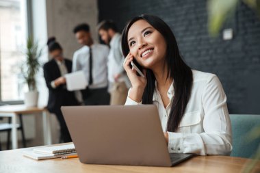 Mutlu genç Asya iş kadın cep telefonuyla söz.