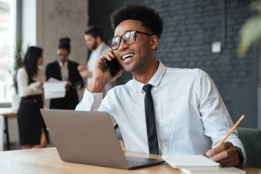 Telefonla konuşurken gülümseyen genç Afrika iş adamı.