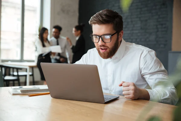 Excited young caucasian businessman sitting indoors — Stock Photo, Image