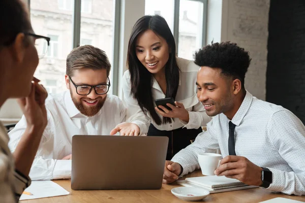 Queridos colegas jóvenes positivos utilizando ordenador portátil . —  Fotos de Stock