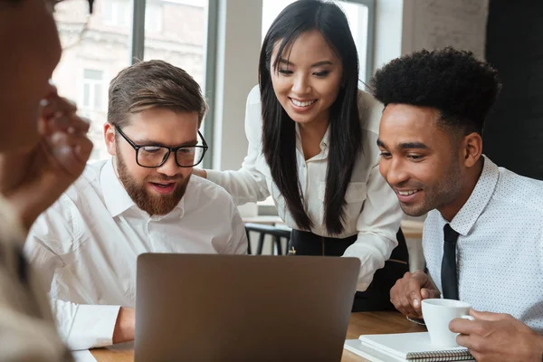 Felices jóvenes colegas de negocios utilizando ordenador portátil . — Foto de Stock