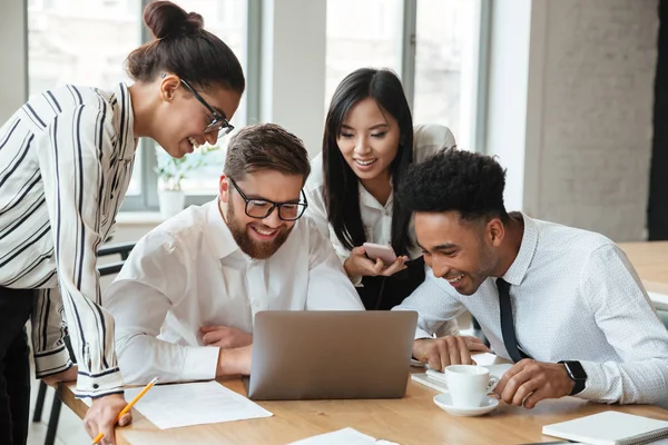 Felices jóvenes colegas de negocios utilizando ordenador portátil . — Foto de Stock