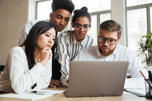 Concentrated serious young business colleagues using laptop computer. — Stock Photo, Image