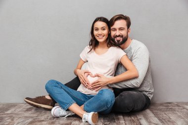 Yakışıklı adam onun hamile eşi ile gülümseyen kalp jest yapmak.