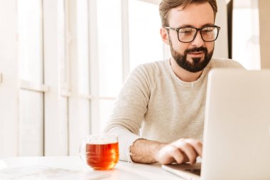 Fotoğraf çekici tıraşsız adamın çay içme gözlük takıyor