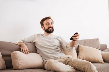 Uzaktan kumanda tutarak gülümseyen bir adam portresi