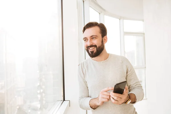 Communicative guy with in white shirt, looking through big windo — Stock Photo, Image