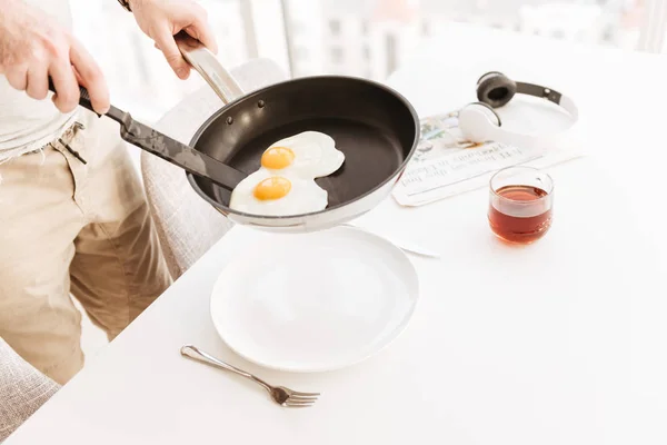 Обрезанное фото человека в повседневной одежде, помещающего яйца в — стоковое фото