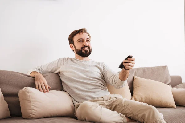 Retrato de um homem sorridente segurando controle remoto — Fotografia de Stock