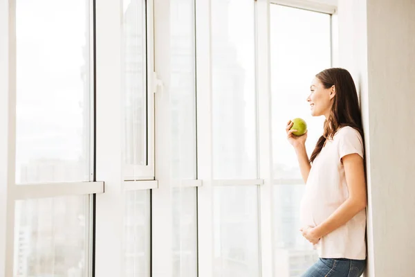 Sourire jeune femme enceinte mangeant de la pomme verte — Photo