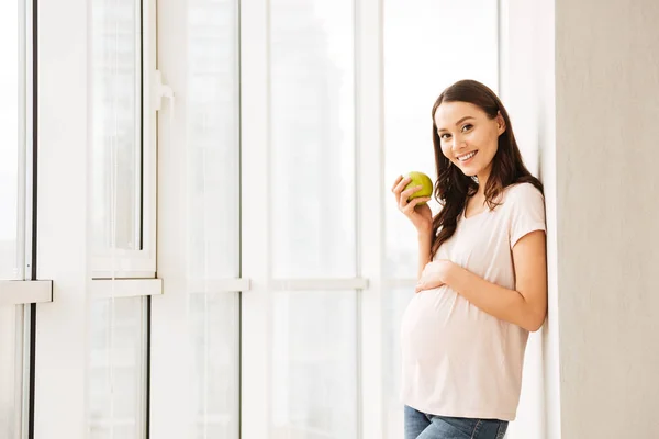 Glad gravid ung kvinna som innehar grönt äpple — Stockfoto