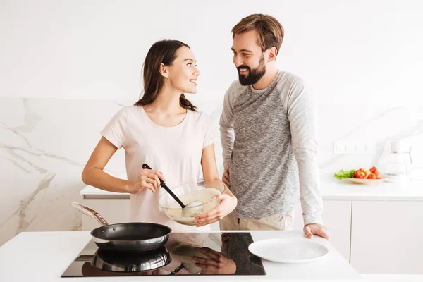 Feliz casal jovem cozinhar panquecas juntos — Fotografia de Stock
