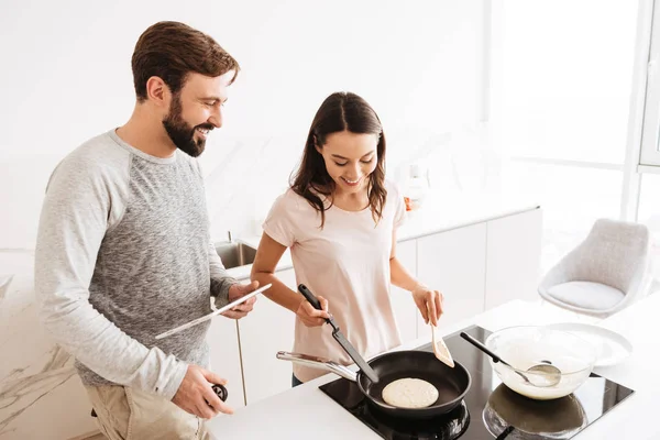 Jovem alegre casal cozinhar panquecas juntos — Fotografia de Stock