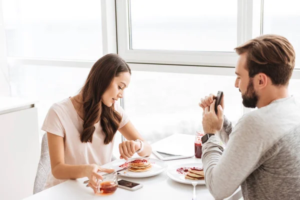 一緒に座って朝食を持っているかなり若いカップル — ストック写真