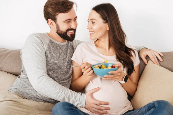 Glada unga gravida par avkopplande på en soffa — Stockfoto