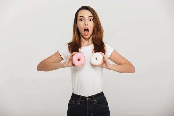 Удивлённая молодая женщина с пончиками перед грудью . — стоковое фото