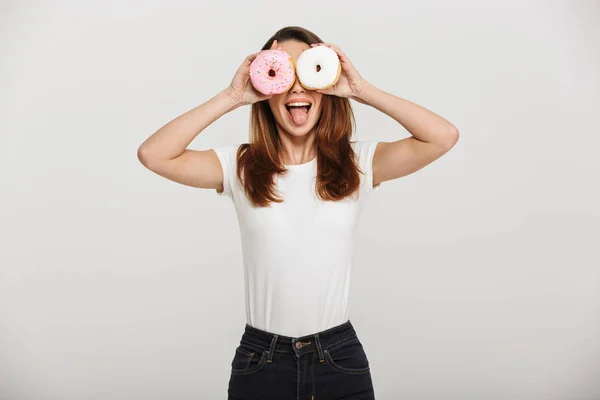 Милая молодая женщина, стоящая с пончиками перед глазами . — стоковое фото