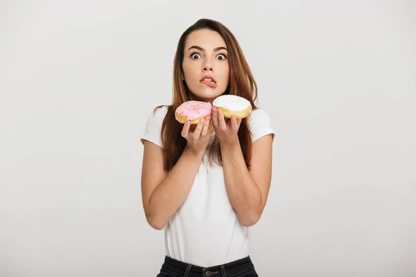 Hungry young lady holding donuts — Stock Photo, Image