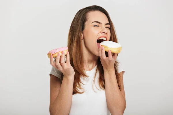 Hungrige junge Frau isst Donuts — Stockfoto
