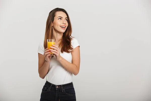 Vrolijke jonge dame op zoek opzij drinken sap. — Stockfoto