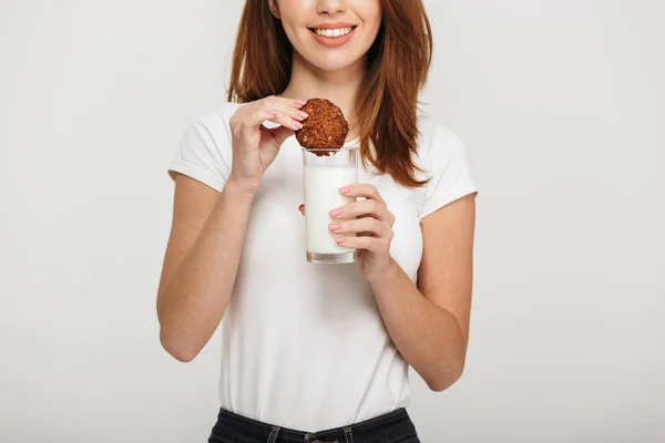 Oříznutí fotografie roztomilé mladé ženy jíst cookie konzumní mléko. — Stock fotografie